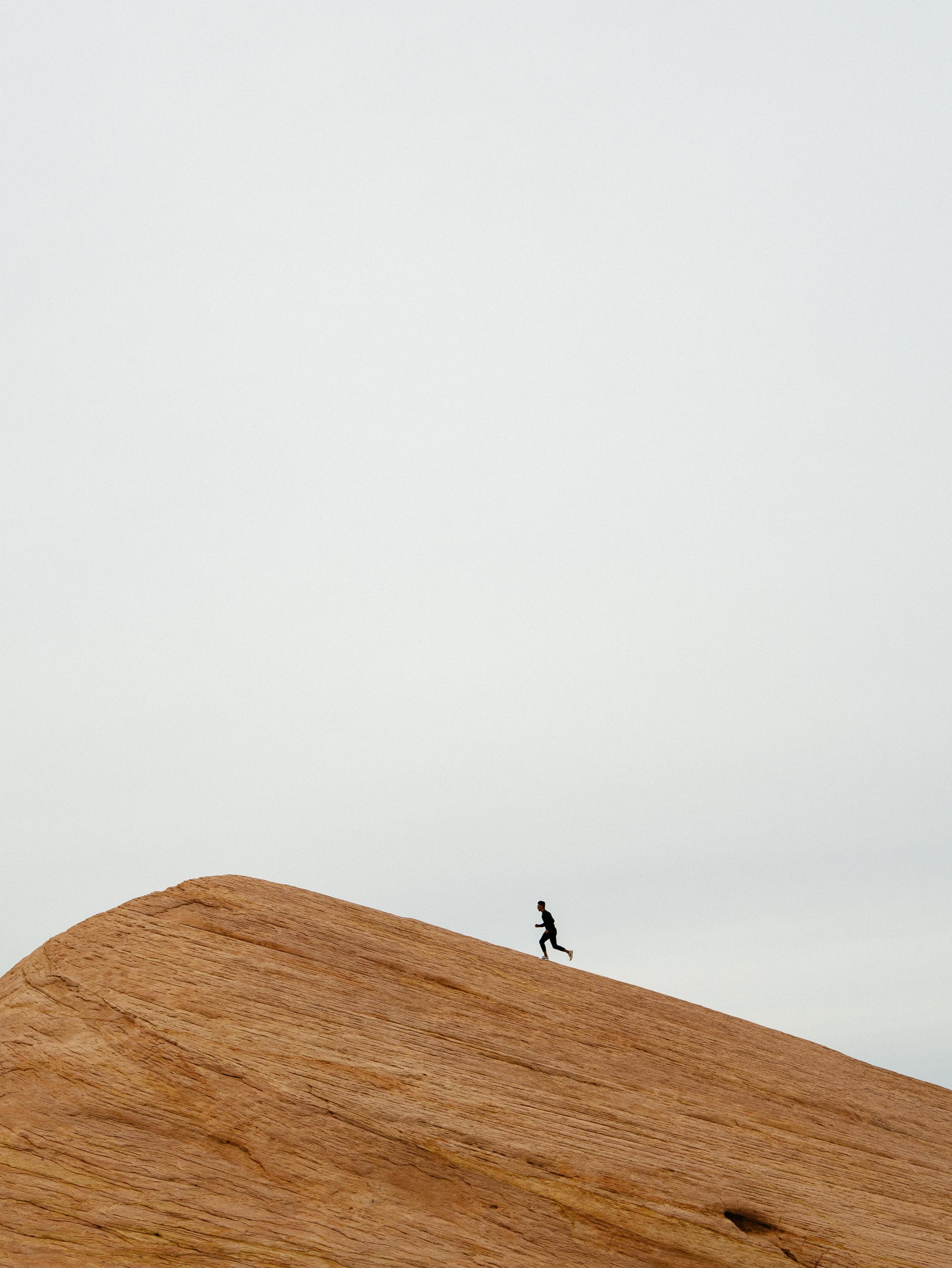 Stock photo of man running up sand dune